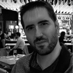 Álvaro Rodríguez, un hombre de pelo corto y oscuro y barba, está sentado en un restaurante con un bar al fondo, mirando directamente a la cámara.