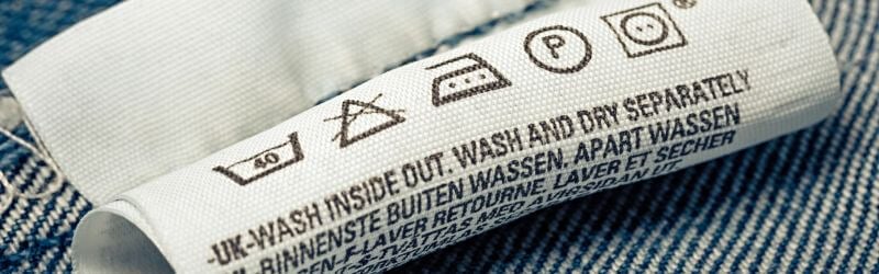 Etiqueta de cuidado de la ropa con símbolos de lavado e instrucciones para lavar del revés y por separado.