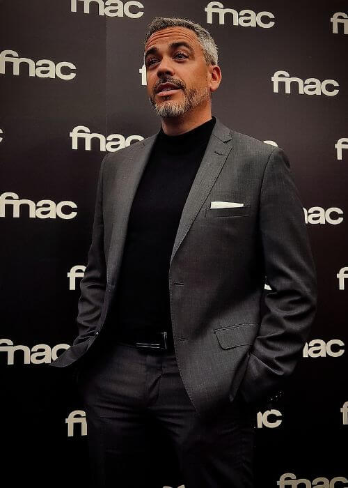 Luis Andalucía, con un traje gris, aparece con las manos en los bolsillos frente a un fondo de fnac.