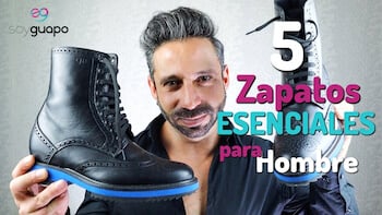 Rubén Lara con una bota negra en cada mano, con el texto "5 Zapatos esenciales para Hombre" sobre fondo gris. Estilo Guido Maggi.